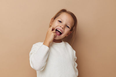 Girl scratching face against beige background