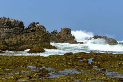 Scenic view of rocks in sea against clear sky