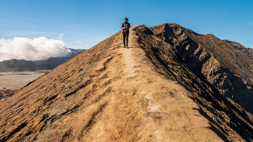 Low angle view of man standing on mountain against sky