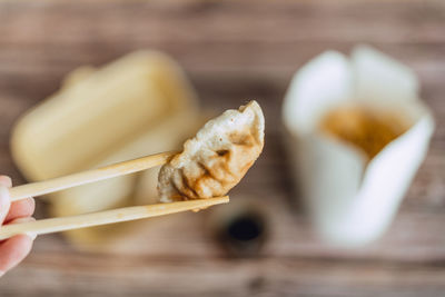 Close-up of hand holding a gyoza with chopsticks