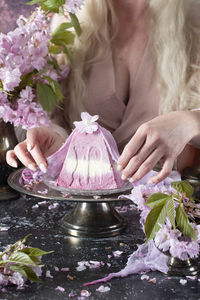 Traditional easter orthodox curd cake with sakura flowers, woman decorating food