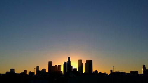 Low angle view of silhouette city against clear sky during sunset