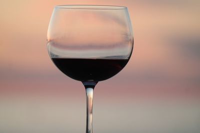 Close-up of wineglass on table against sky during sunset