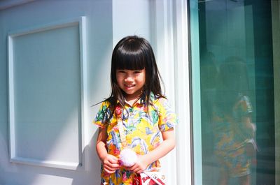 Portrait of smiling woman standing against window