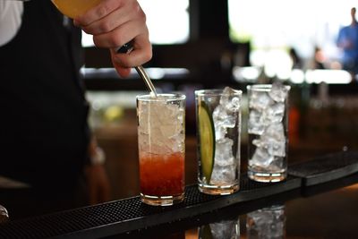 Midsection of man mixing liquid in drink at restaurant