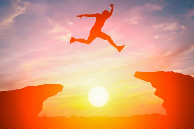 Low angle view of silhouette man jumping against sky during sunset