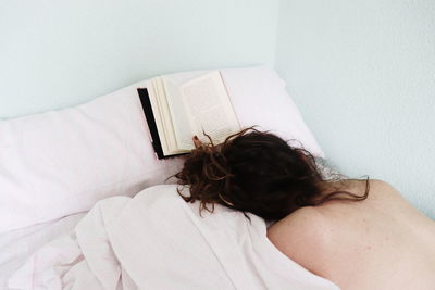 Rear view of woman lying on bed at home