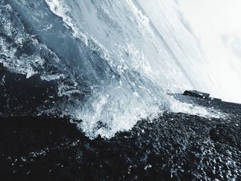 Aerial view of sea waves splashing on snowcapped mountain