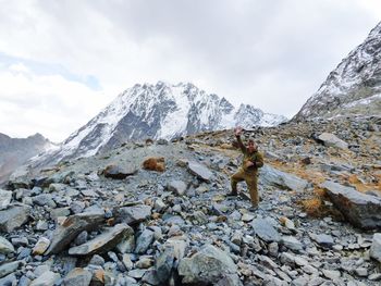 Person standing on rock against sky during winter