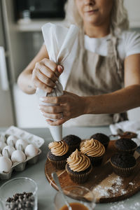 Woman putting icing on cupcakes