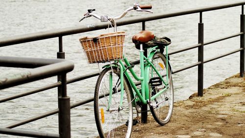 Bicycle parked by railing against wall in city