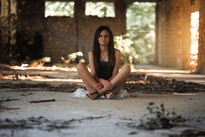 Portrait of young woman sitting in abandoned building