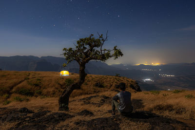 Tree on field against sky at night