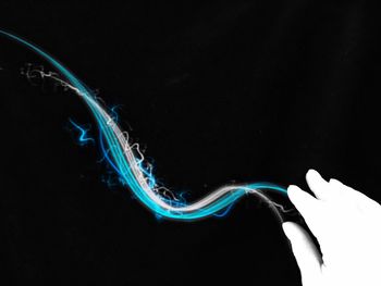 Close-up of hands swimming in water against black background