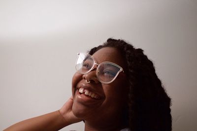 Portrait of woman holding eyeglasses against white background