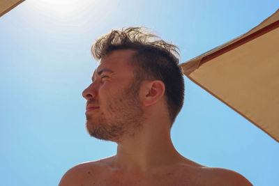 Portrait of shirtless man against sky