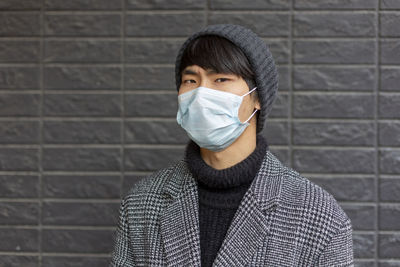 Portrait of man wearing mask against brick wall