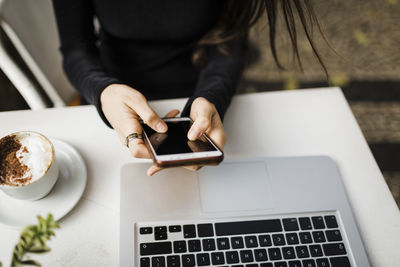 Midsection of woman using mobile phone at table