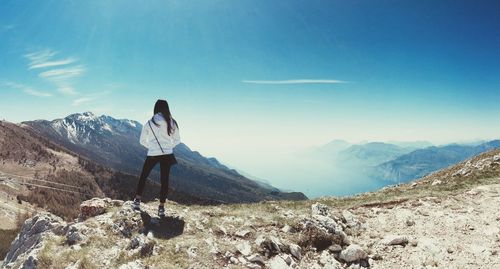 Rear view of man standing on rock against sky