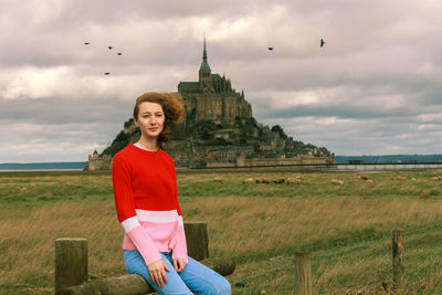 Portrait of young woman on land against the mont-saint-michel