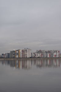 Buildings by river against sky in city