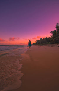 Rear view of man on beach against sky during sunset