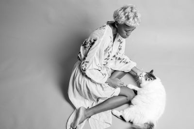 High angle view of woman with cat sitting against white background