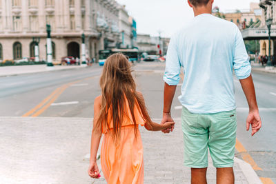 Rear view of couple walking on street in city