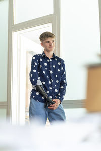 Boy with amputated arm leaning on door