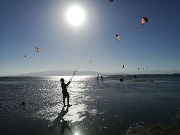 Silhouette man kiteboarding at beach during sunset