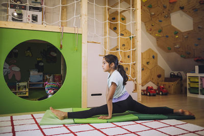 Active girl doing splits while exercising at home