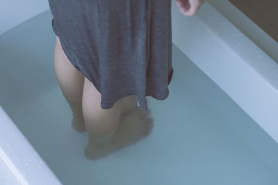 Low section of woman standing in bathtub