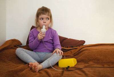 Sick child lies in bed and makes inhalation using a nebulizer. treatment of bronchitis