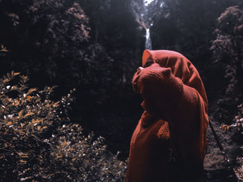 Side view of woman standing by trees in forest