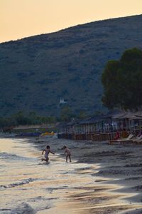 People on beach against clear sky