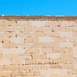 Low angle view of brick wall against clear blue sky