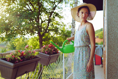 Woman wearing hat standing against trees