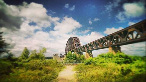 Bridge over river against cloudy sky