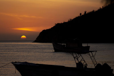 Silhouette boat in sea against orange sky