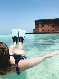 Rear view of woman floating on water against sky