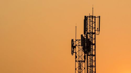 Low angle view of silhouette electricity pylon against sky during sunset