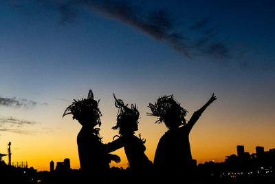 Silhouette statue by tree against sky during sunset