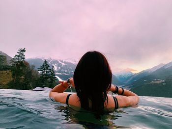 Portrait of woman in swimming pool against sky during sunset