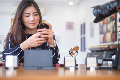 Young woman using phone on table