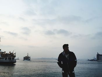 Man standing on boat in sea against sky