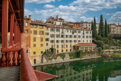 Buildings by river against cloudy sky