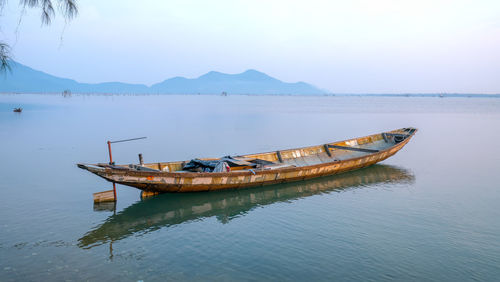 Boat moored in lake against sky