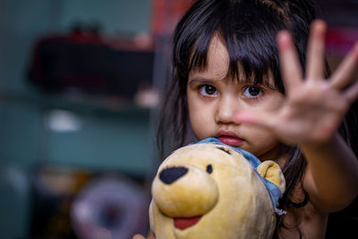 Portrait of girl holding toy and gesturing at home 