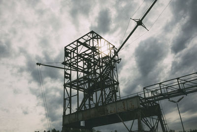 Low angle view of crane against cloudy sky