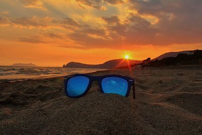 Sunglasses on sandy beach at sunset